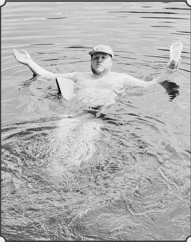 Zach M. floating in the lake, arms outstretched.