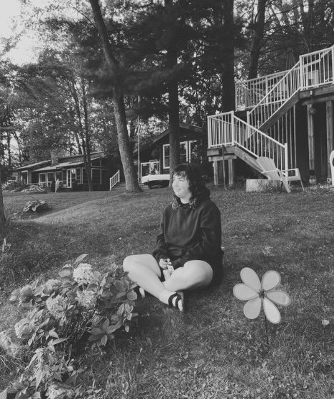 Megan S. sitting on the lawn in front of the cottage.