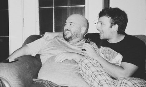 Two men laughing on a couch.